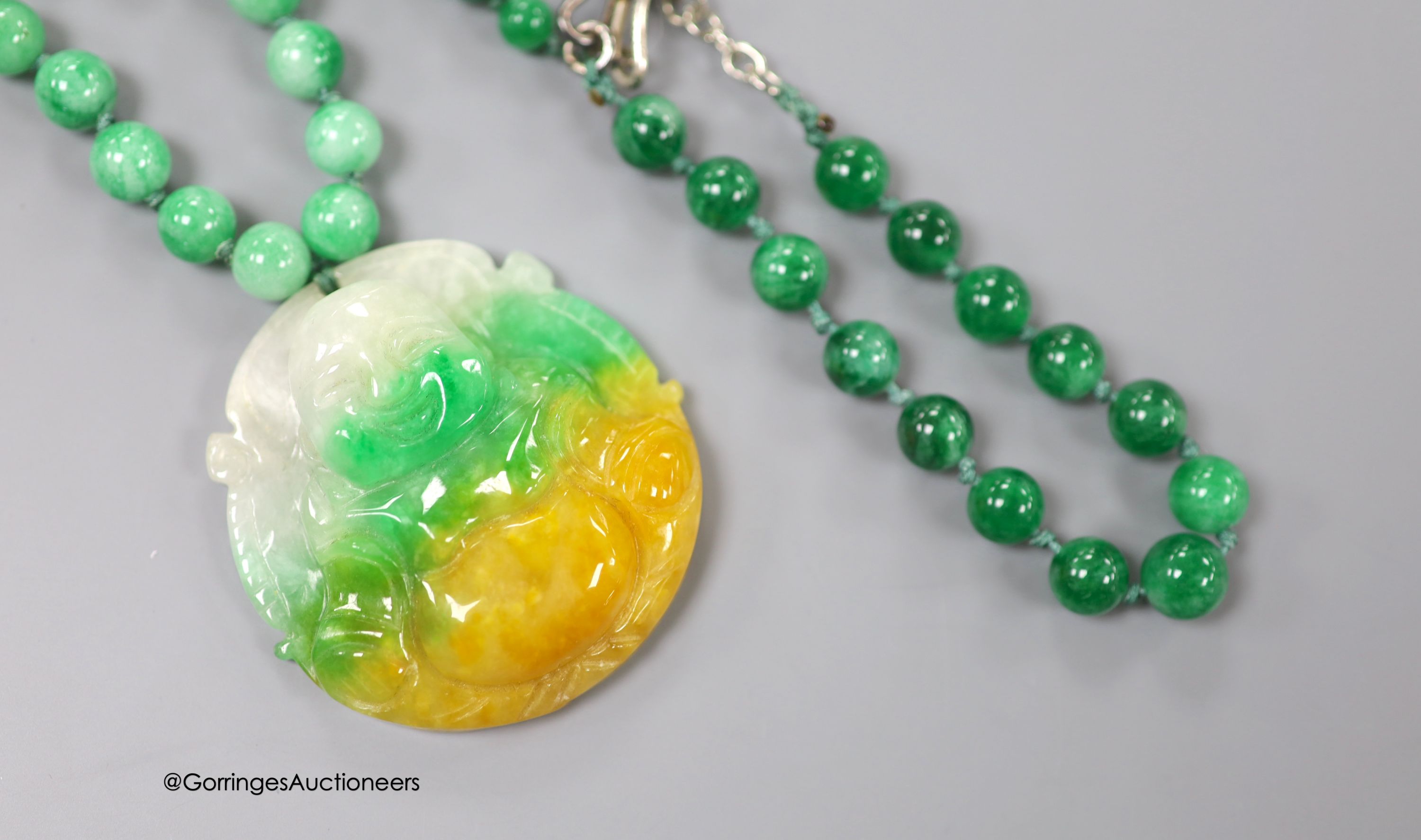 A jade pendant, carved as a Buddha, 50mmm, on a jade bead necklace, 50cm, together with a jade bead bracelet.